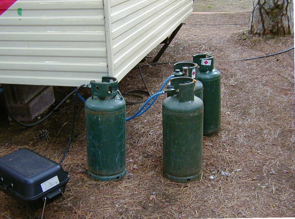Two gas bottles connected to a portable stove set up outdoors.