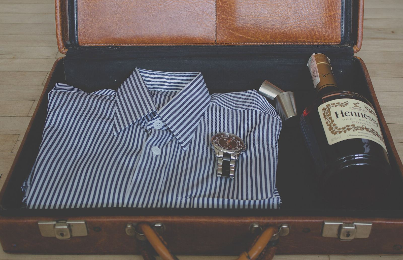 An open suitcase packed with a folded striped shirt and travel items.