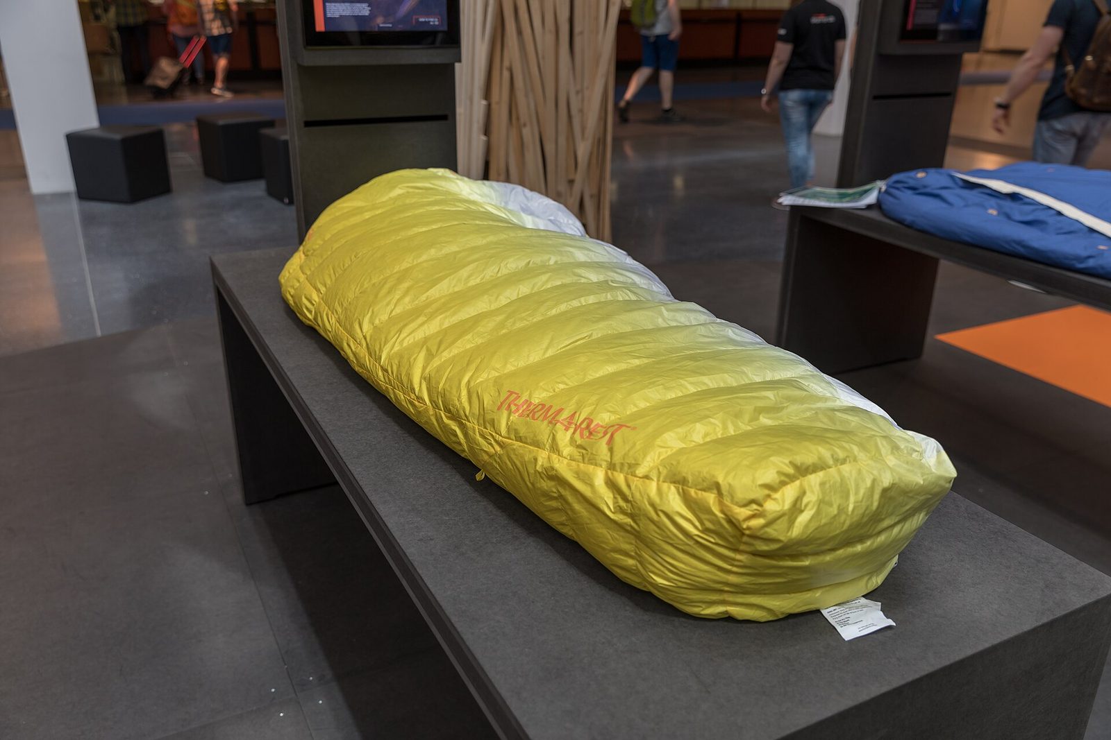 A packed sleeping bag displayed on a stand at an outdoor gear show.