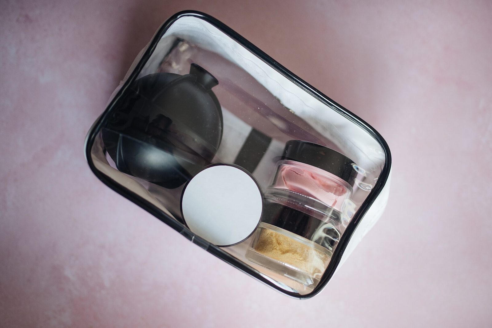 A clear toiletry bag organised with small travel products.