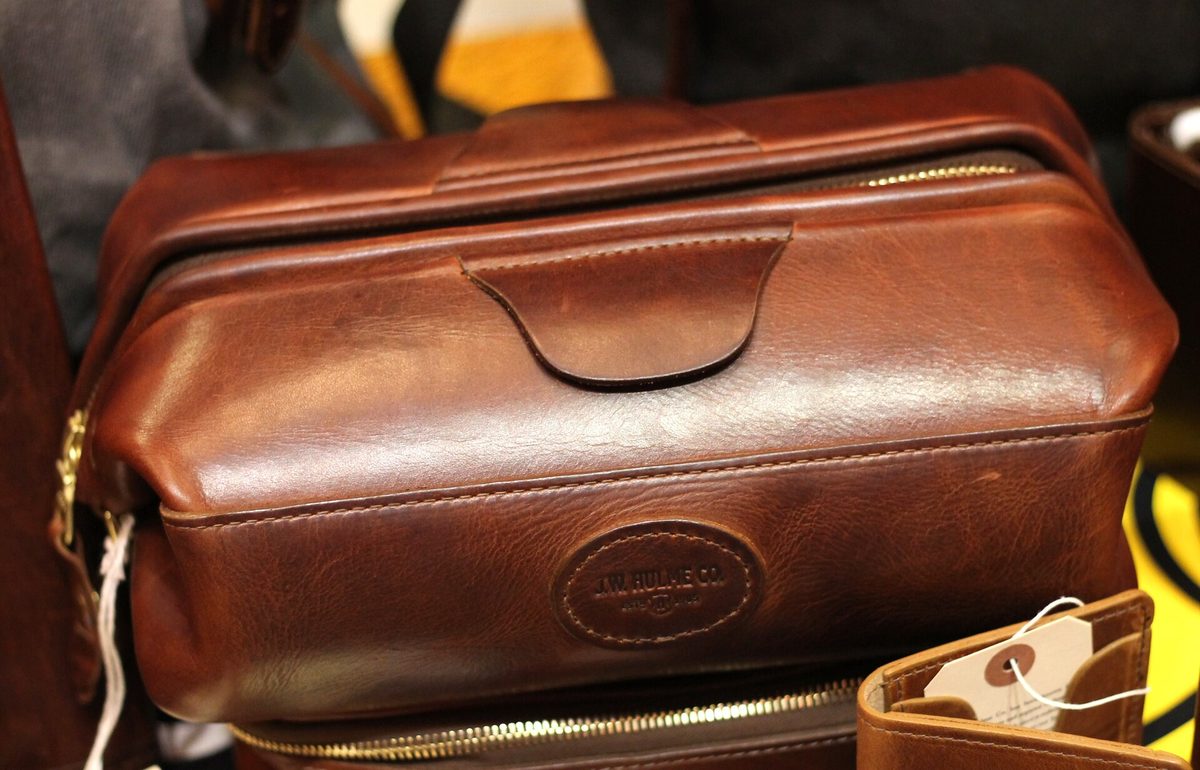 A compact leather wash bag that holds a travel toiletry kit.